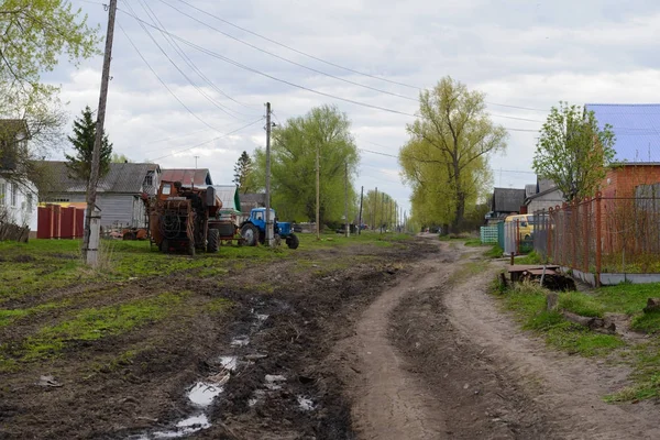 6 maj 2017: foto av bygatan som med en traktor och grusväg. Kivsert-Yanishevo. Ryssland. — Stockfoto