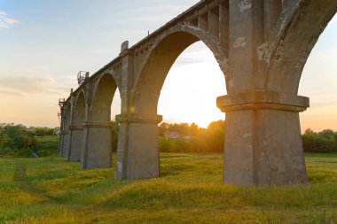 Bir yaz akşamında tarlanın üzerinde eski kemerli bir köprü