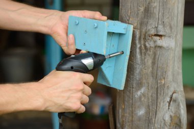 Erkek eli, tornavidayla ahşap bir raf hazırlar.