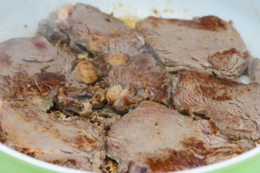 Beyaz tavada ızgara sulu et parçaları.