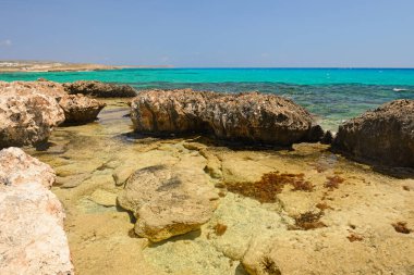 Akdeniz kıyısında turkuaz suyla kayalık bir sahil.