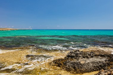 Akdeniz kıyısında turkuaz suyla kayalık bir sahil.