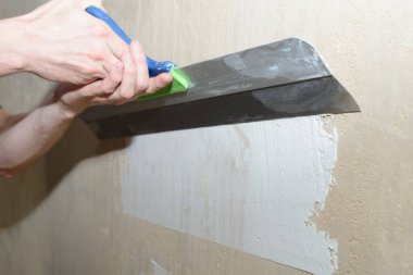 Geniş bir spatula kullanarak duvarı beyaz alçı macunla kaplamak.