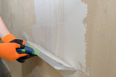 Geniş bir spatula kullanarak duvarı beyaz alçı macunla kaplamak.