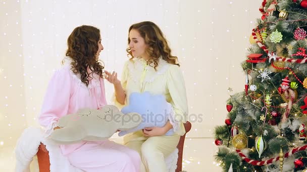 Две девушки веселятся в пижаме рядом с елкой — стоковое видео