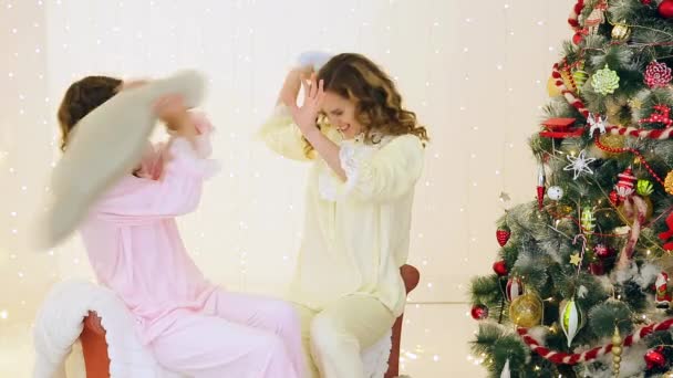 İki kız onların pijama Noel ağacı yakınındaki eğleniyor — Stok video