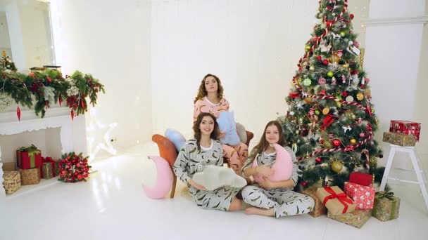 Tres chicas divirtiéndose en pijama cerca del árbol de Navidad — Vídeos de Stock