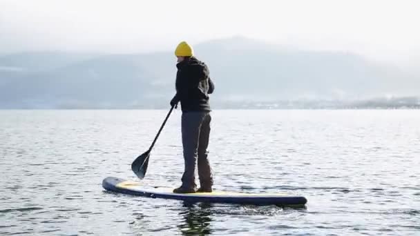 Дівчина плаває на борту sap на озері зими в Сибіру — стокове відео