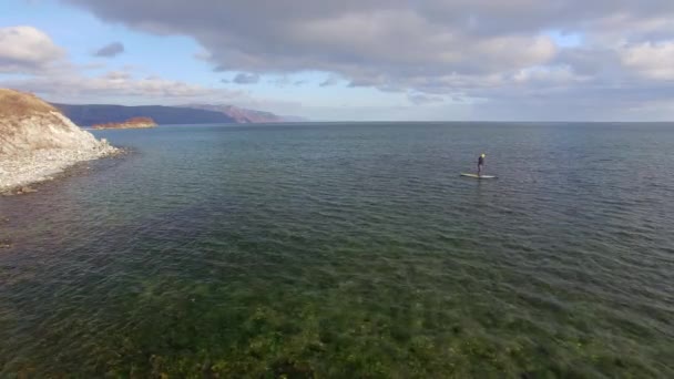 4K. Aero. A menina flutua na tábua de seiva no lago de inverno na Sibéria — Vídeo de Stock