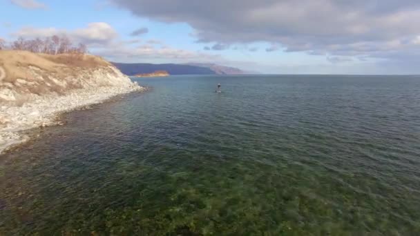 4K. Aero. La chica flota en el tablero de la savia en el lago de invierno en Siberia — Vídeos de Stock