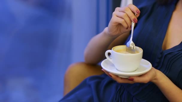 Prores. Una joven con un vestido azul está tomando café en un café. — Vídeos de Stock