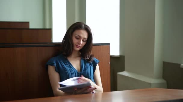 Prore. Una giovane ragazza in abito blu sta studiando materiale didattico tra il pubblico — Video Stock