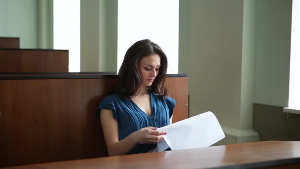 Prores. Une jeune fille en robe bleue étudie le matériel éducatif dans le public — Video