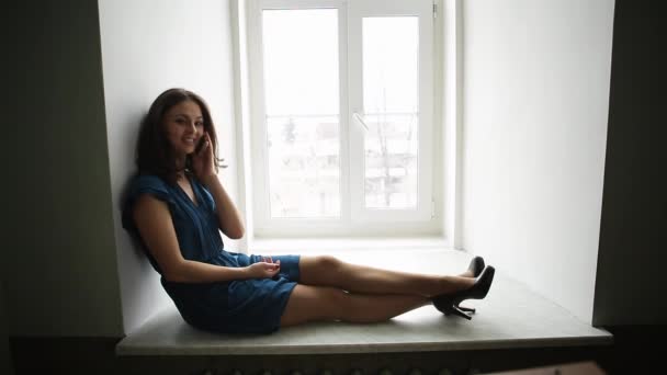 ProRes. Egy fiatal lány, egy kék ruhás beszél egy okostelefon, az ablak — Stock videók