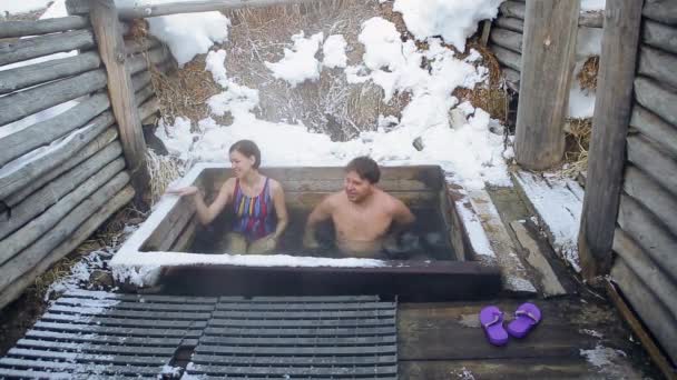 Códec de Prores. Un hombre y una niña toman un baño de aguas termales naturales al aire libre en invierno — Vídeo de stock