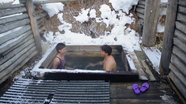 Prones codec. Мужчина и девушка принимают ванну с горячими природными минеральными источниками на открытом воздухе зимой — стоковое видео