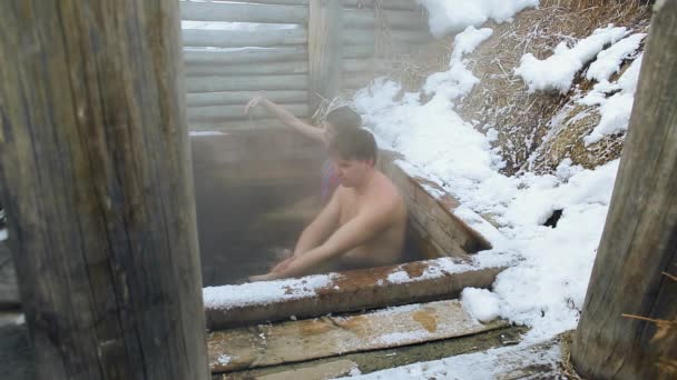 Códec de Prores. Un hombre y una niña toman un baño de aguas termales naturales al aire libre en invierno — Vídeo de stock