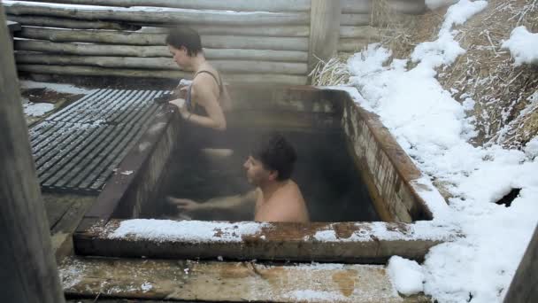 Вимагає кодек. Чоловік і дівчина приймають ванну гарячих природних мінеральних джерел на відкритому повітрі взимку — стокове відео
