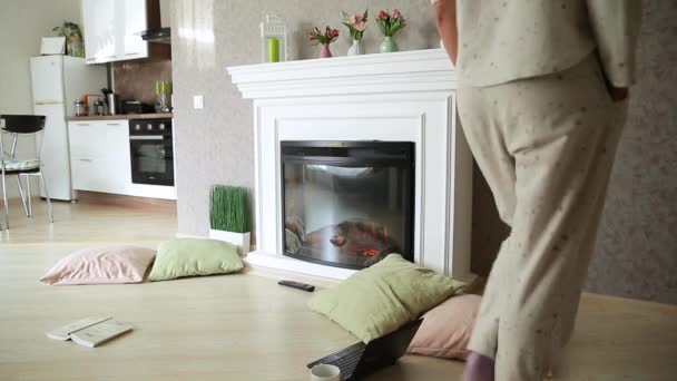 一个穿着浅色睡衣的女孩在壁炉旁的家中镗孔 — 图库视频影像