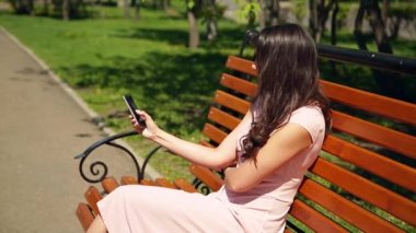 Yaz. Pembe elbiseli bir genç kız parkta bir bankta oturuyor