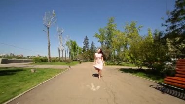 Yaz. Pembe elbiseli romantik bir kız elini kolunu sallaya nehir set dönüyor