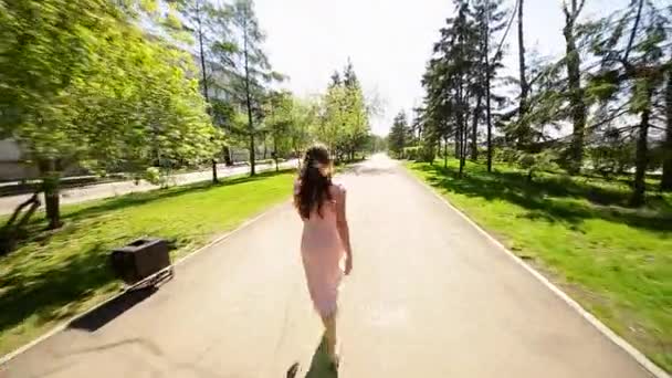 L'été. Une fille romantique en robe rose se promène le long du remblai de la rivière 