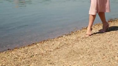 Yaz. Pembe elbiseli romantik bir kız elini kolunu sallaya nehir set dönüyor