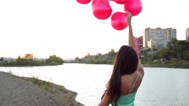 赤い気球の街と川を背景にポーズをとって長い緑のドレスの女の子 — ストック動画