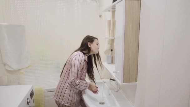 在家里的浴室里 穿着粉色睡衣 一头长长的黑头发的小女孩洗牙洗得很开心 — 图库视频影像