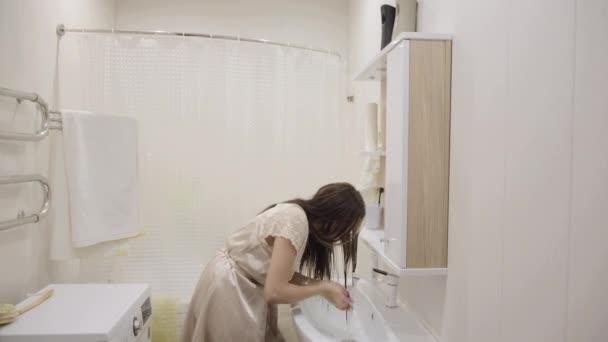 年轻的黑发姑娘 穿着鲜艳的衣服 在家里的浴室里洗着有趣的衣服 — 图库视频影像