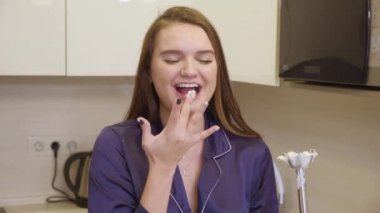 Uzun siyah saçlı ve mavi elbiseli kız apartmanın mutfağında sağlıklı bir kahvaltı hazırlıyor.