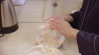 Mavi elbiseli bir kızın ellerine yakın çekim. Daire mutfağında sağlıklı kahvaltılık süzme peynir pişiriyor.