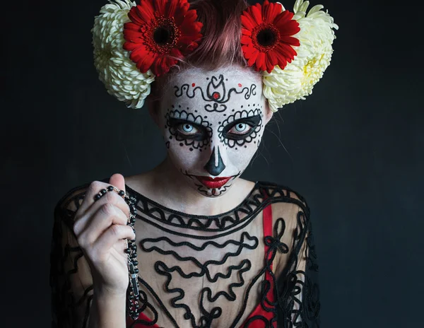 Fotografía aterradora de una hermosa chica con un patrón en la cara y flores rojas en el pelo Los Muertos — Foto de Stock