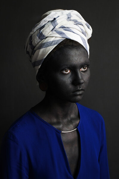 Photo portrait of a girl in a white turban and a blue blouse painted dark gray paint skin