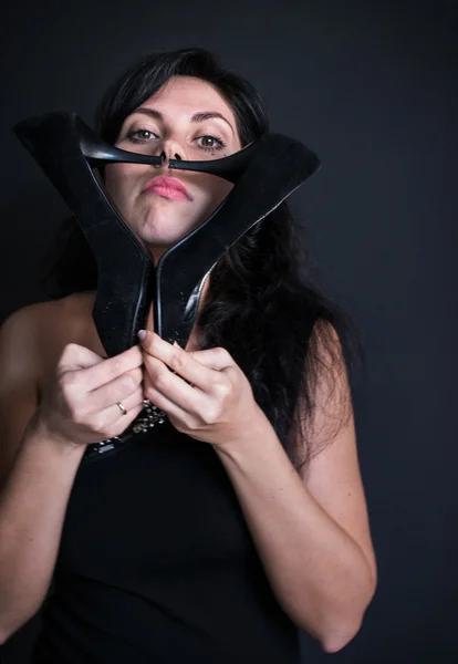 Retrato fotográfico de un modelo de pelo oscuro en vestido negro en un hombro con tacones altos tuflemi supervisión de la cara como un bigote — Foto de Stock