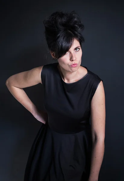 Foto mujer en un vestido negro con una mano de peinado alto en la cintura — Foto de Stock