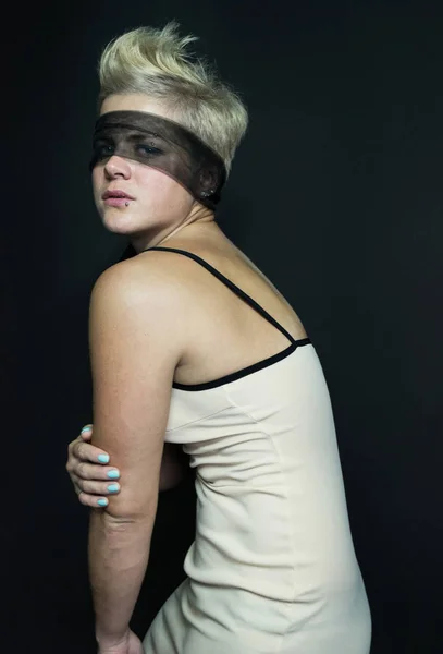 Foto rubia chica en un vestido beige transparente negro ojos vendados posando — Foto de Stock