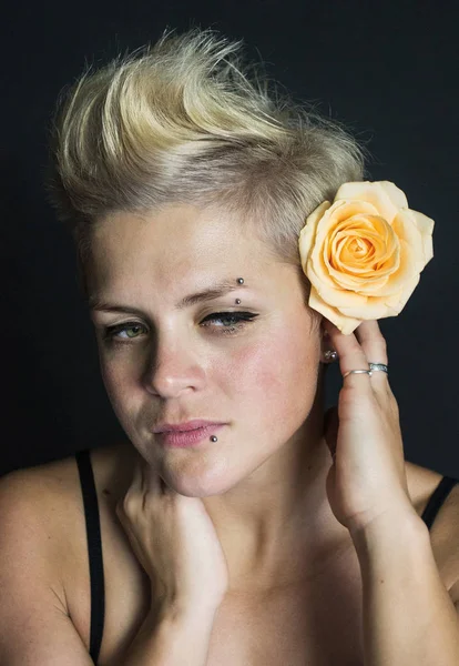 Foto retrato de una rubia de pelo corto con una rosa en el pelo con piercing — Foto de Stock