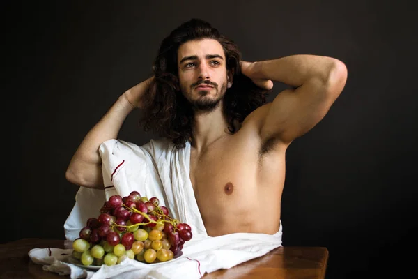 Foto hermoso chico desnudo con pelo largo rizado con cortinas blancas y un plato de uvas alisa el cabello — Foto de Stock