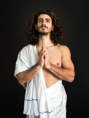 Fotoğraf beyaz bir perdelik kıvırcık saçlı bir adam ellerini dua katlanmış.