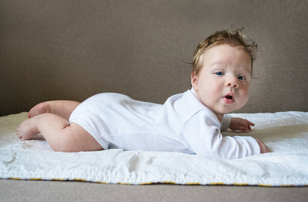 photo baby in white clothes lies belly down