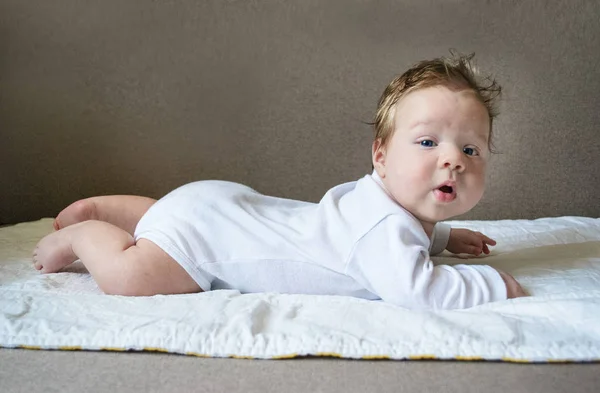 Foto bebé en blanco ropa yace vientre abajo — Foto de Stock