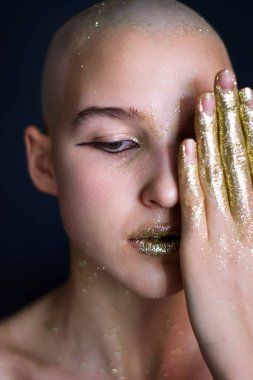 Çıplak, kel, altın sarısı, parlak elleri olan kız yüzünü örttü.