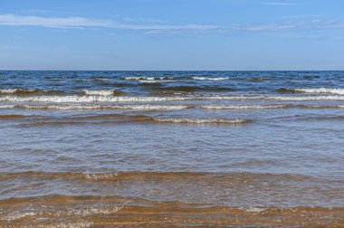 Deniz dalgaları parlak mavi gökyüzüne karşı