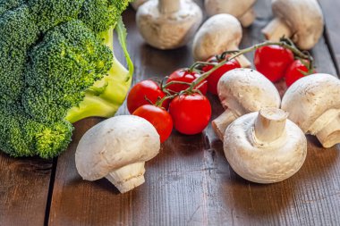 Brokoli, mantar ve sert ahşap bir yüzey üzerinde kiraz domatesleri.