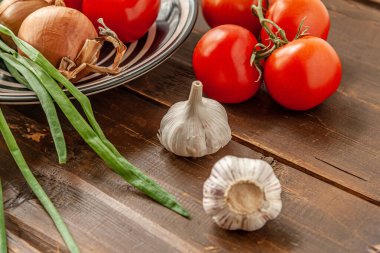 Tahta bir masada domates, soğan ve sarımsak dolu bir hayat