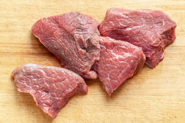 Tahta kesme tahtasının üzerinde çiğ et parçaları yatıyordu.