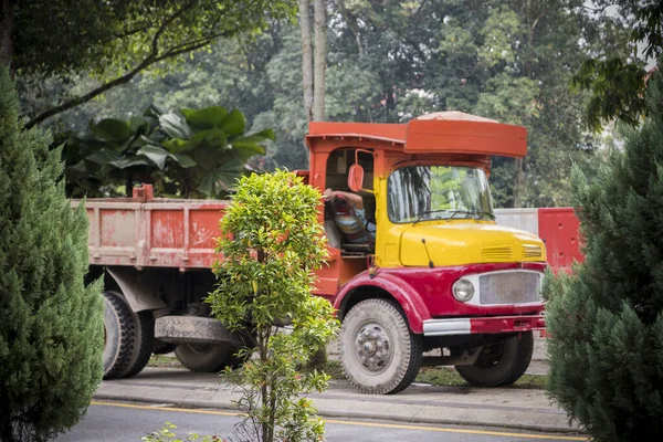Driver sleeps in an old Asian truck made of wood in red and yellow. Kuala Lumpur, Malaysia.