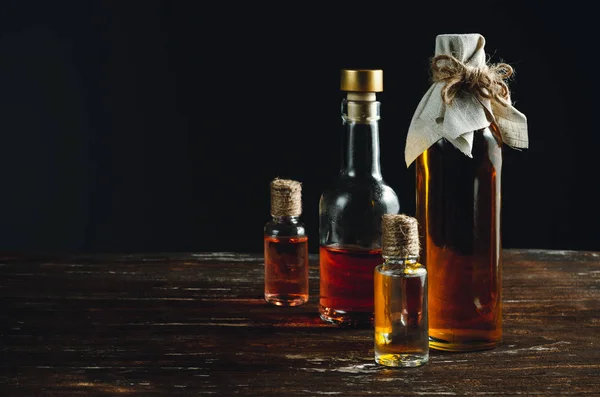 Several bottles with oil stand in a group on a wooden table. — Stock Photo, Image