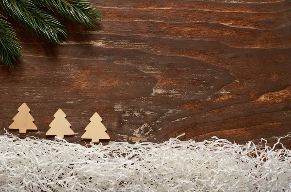 Ветвь ели, имитация снега из бумаги и деревянные елки на старинном деревянном фоне . — стоковое фото